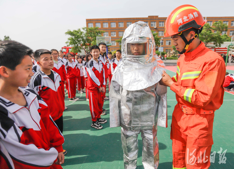 2021年5月11日,河北省遵化市第一中学崔家庄初中分校的学生,在消防救援人员的指导下体验消防救援防护服。