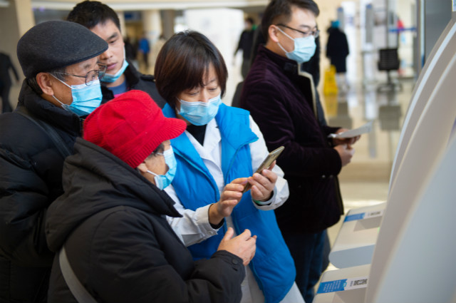 2020年12月9日，首都医科大学附属北京天坛医院的工作人员帮助老年人使用手机缴费。新华社图。