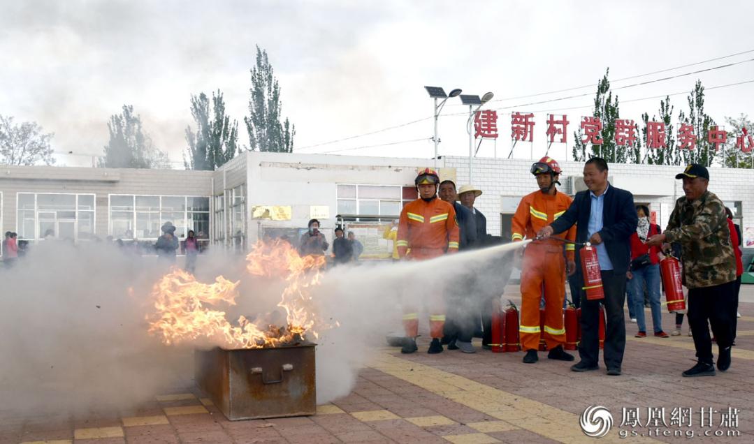 消防员指导村民使用干粉灭火器扑灭熊熊燃烧的大火 贾永平 摄