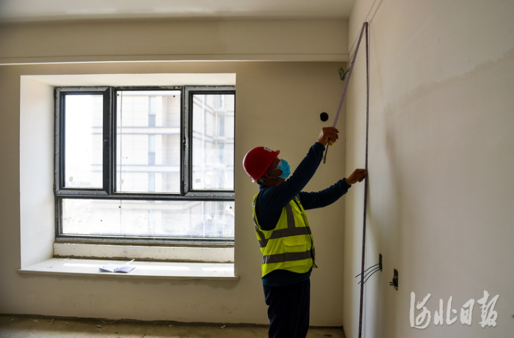 2021年5月17日,雄安新区容东片区中建三局G2安置房项目,三工区综合工长涂德宝在检测内部墙面施工情况。