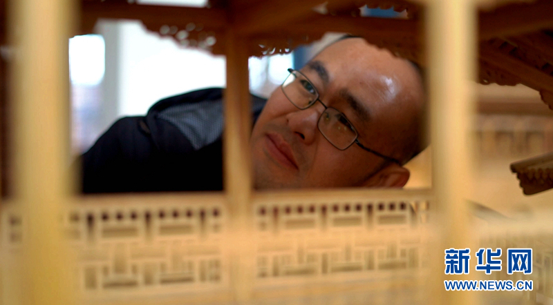 图为丁沙金在查看微缩古建筑作品内部结构