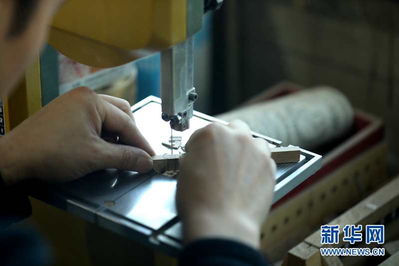 图为团队成员丁延斌用小带锯切割开卯