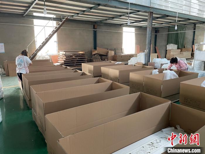 图为，庄寨镇一工厂工人正在打包棺木。　孙宏瑗 摄