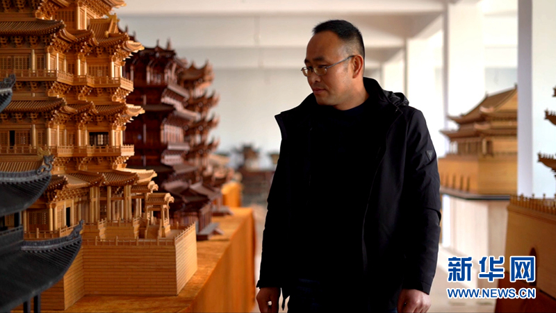 图为丁沙金在传习所展厅内观看微缩古建筑作品