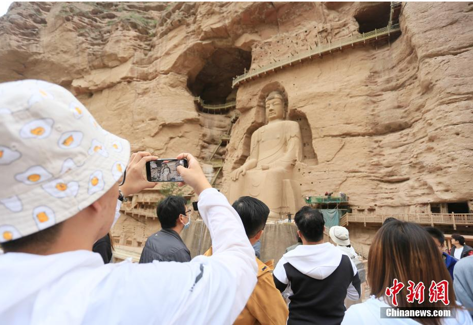 6月2日，在大陆创业、学习的台湾青年走进位于甘肃省临夏回族自治州永靖县的世界文化遗产炳灵寺，体验石窟文化。图为台青参观炳灵寺内最大石窟佛像。中新社记者 高展 摄