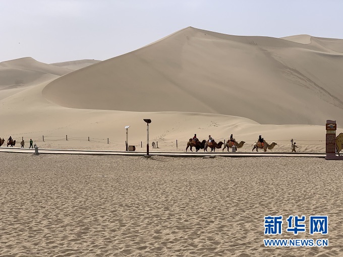 敦煌鸣沙山月牙泉景区内，游客骑着骆驼感受沙漠之美。新华社记者 李杰 摄
