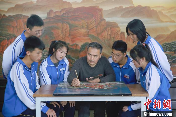 平遥推光漆器协会会长薛晓东正在给学生展示推光漆器技艺。　薛氏漆艺研究院供图