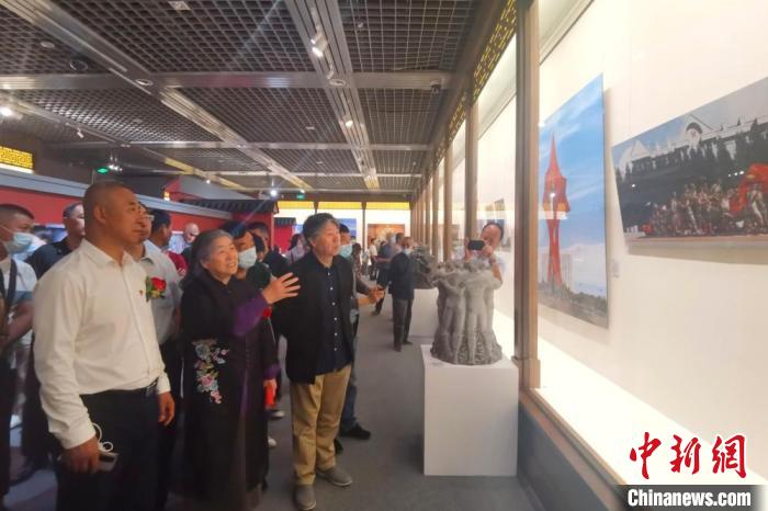 图为雕塑家何鄂(中)介绍其作品创作的背景及意义。　闫姣 摄