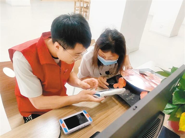 碑林区图书馆的志愿者帮助视障人士操作阅读辅助设备
