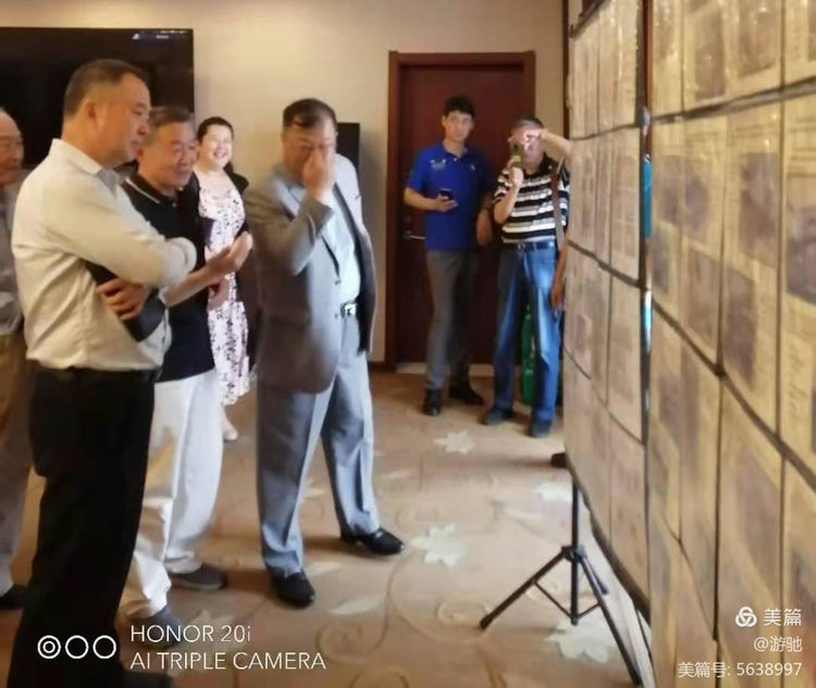 孙振国主任向青岛市文联党组成员、副主席徐健（左）和协会副会长、青铜器专业委员会主任张国枢（中）介绍会员的邮集展品。