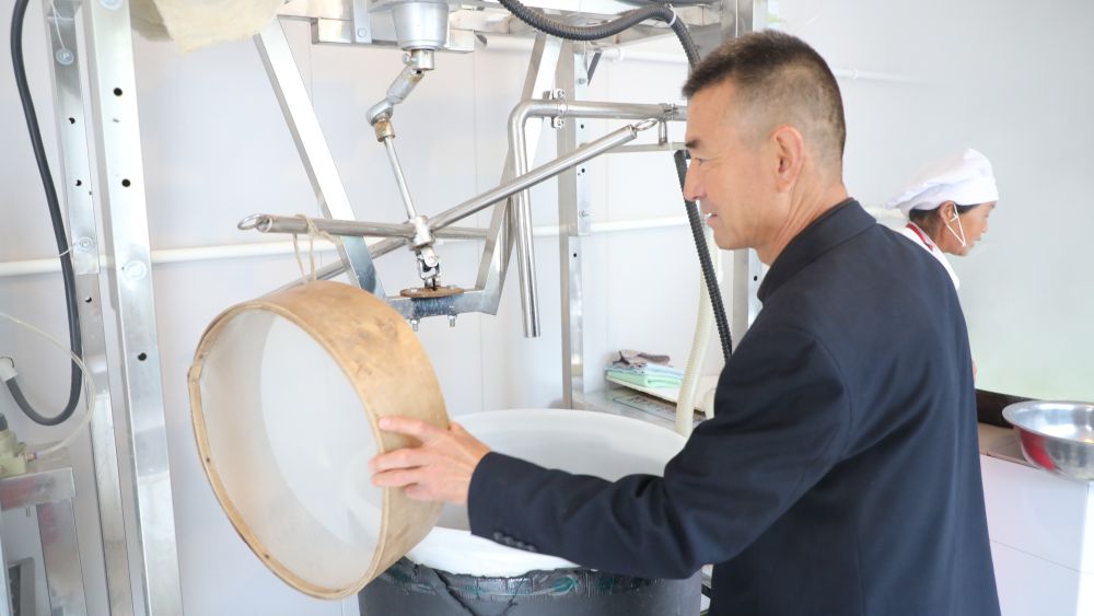 梅建顺（左）正在查看制作豆腐的工具 新华社记者 李杰 摄