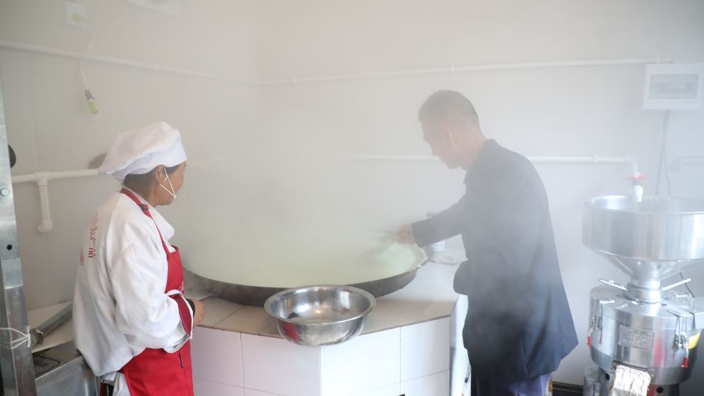 梅建顺（右）正在教授村民制作豆腐 新华社记者 李杰 摄