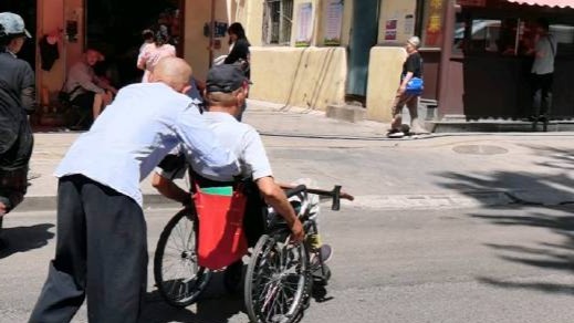 88岁老父亲步履蹒跚为瘫痪儿子推轮椅
