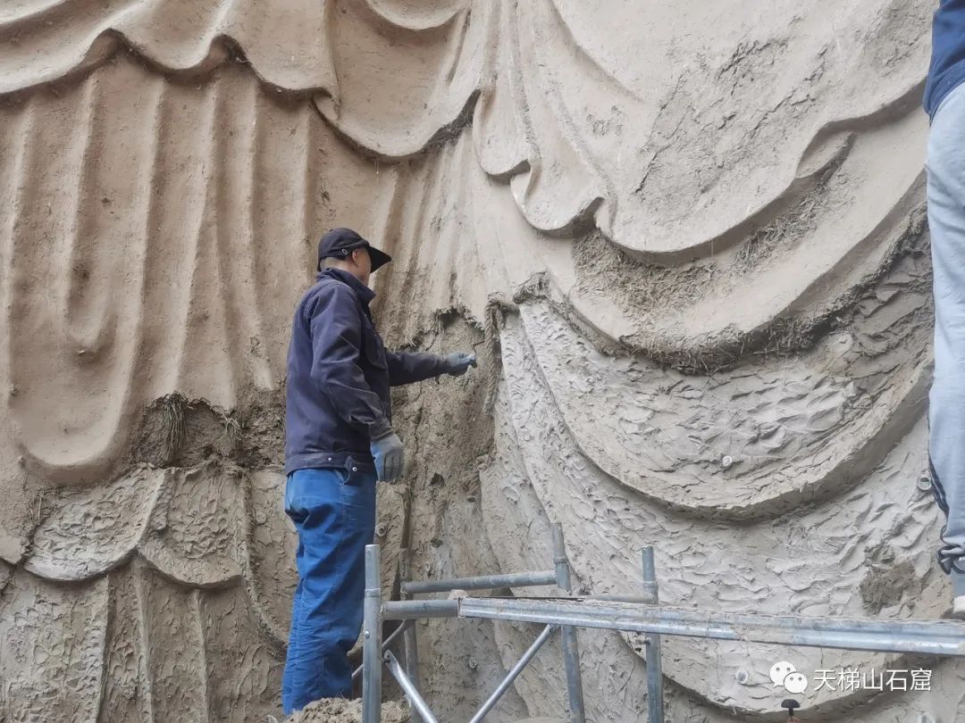 塑像修复师正在对大佛衣褶处补塑泥层（敦煌研究院/供图）