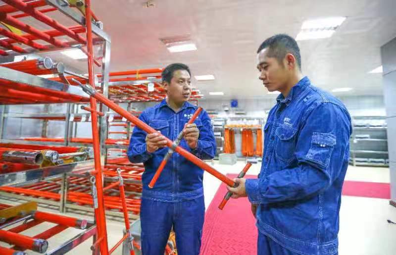 陶留海为同事讲解自主研发的带电作业工器具使用方法（罗浩 摄）