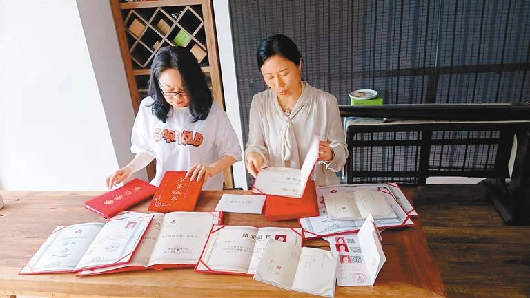 郝永霞（左）和李林在整理陪读妈妈们的各种获奖证书。