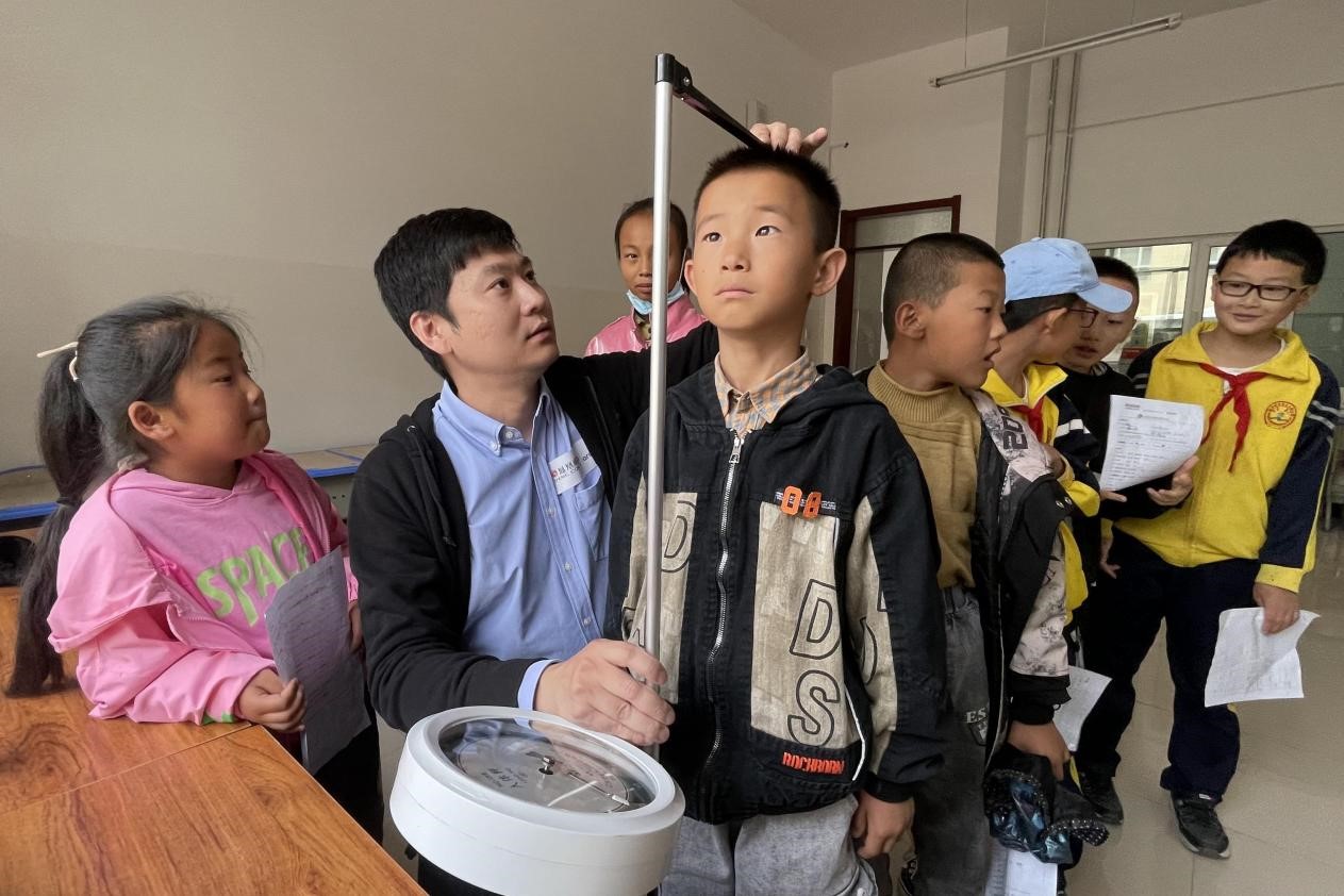 志愿者为孩子进行身高体重检查