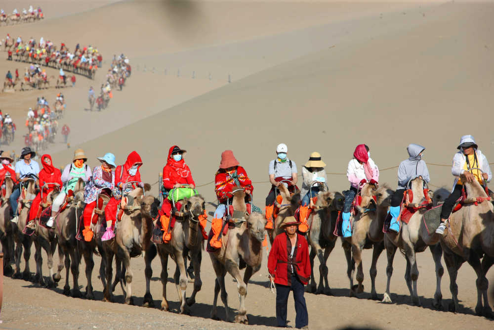 月牙泉边、鸣沙山上骑骆驼的游客 新华社记者 刘诗平 摄
