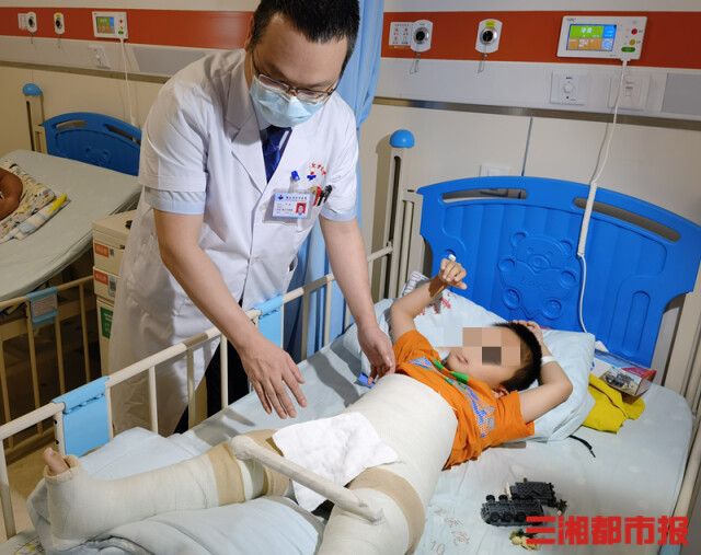 （暑期后，湖南省儿童医院骨折的小患者增多。图为严安副主任医师在为小患者检查。李琪 摄）