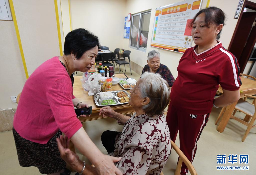 林丹（左一）在社区居家养老服务中心向徐佩英老人了解饮食健康情况（6月23日摄）。新华社记者 林善传 摄