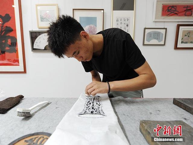 7月28日，魏飒在位于长春市的工作室内进行古砖拓印工作。今年21岁的魏飒是一名拓片师，2019年开始学习古砖拓片制作。魏飒介绍，这些古砖已有千年历史。采用传统方式将古砖上的文字或图案清晰地拓印出来，制作成展品，可以更好地将传统文化保存下来并传递到世界各个角落。 图为魏飒正在对古砖进行拓印 刘栋 摄