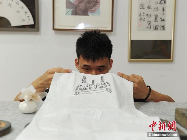 魏飒正在检查拓印后的作品。刘栋 摄