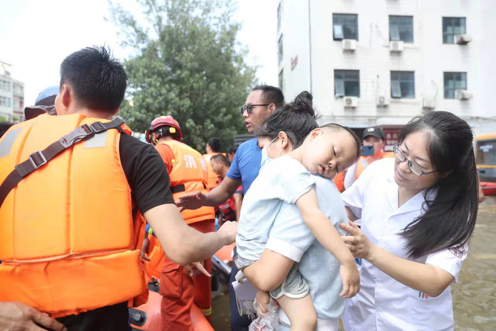 26日下午,新乡医学院第一附属医院住院楼门口,等待转运的孩子趴在妈妈肩膀上。