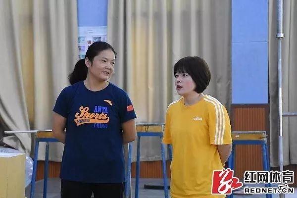 王明娟（右）与周继红（左）在湖南省体育职业学院的湖南省举重运动管理中心训练场地内交流工作。