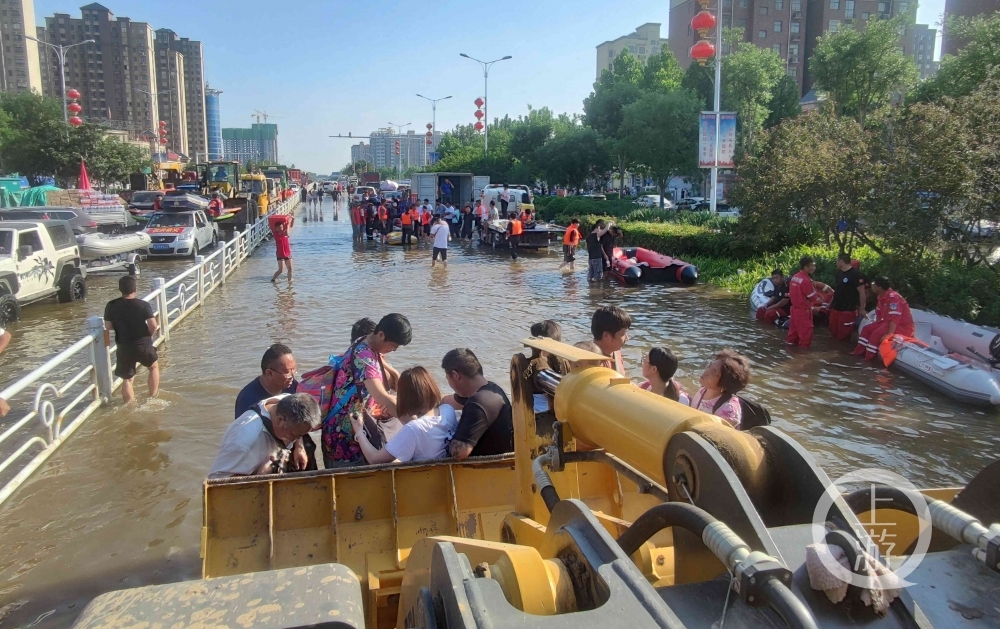 ▲7月25日，河南卫辉市城区比干大道上，铲车正在转移群众。摄影/上游新闻记者 牛泰
