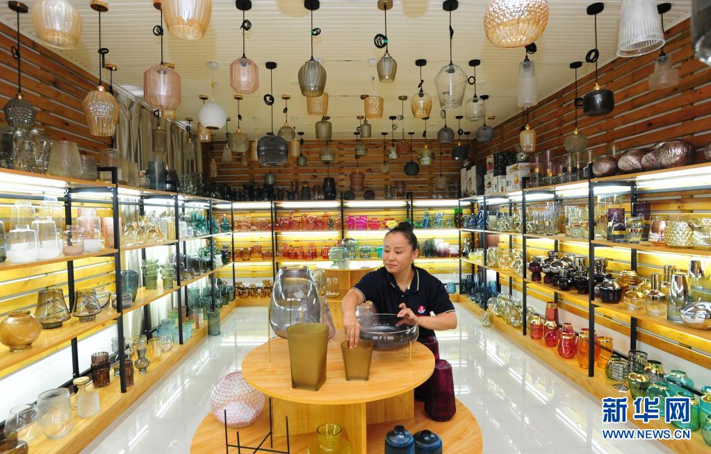 7月28日,在河北省沧州市南皮县一家工艺玻璃制品企业的展室,工作人员在摆放玻璃器皿。