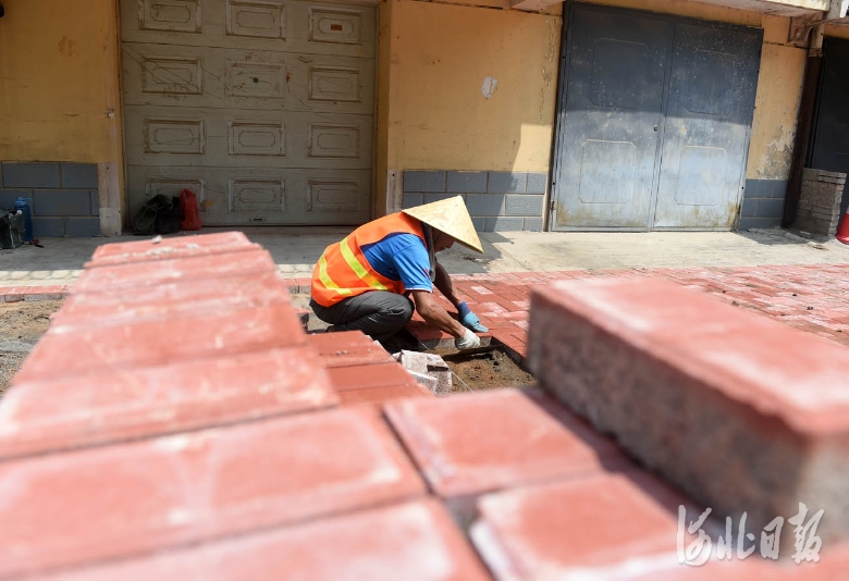 2021年8月1日，河北省邢台市政建设集团工人在老旧小区改造项目——信都区园东小区铺设便道砖。河北日报记者赵永辉摄