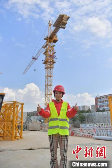 赵丽娟和她所操控的塔吊合影 张瑶 摄