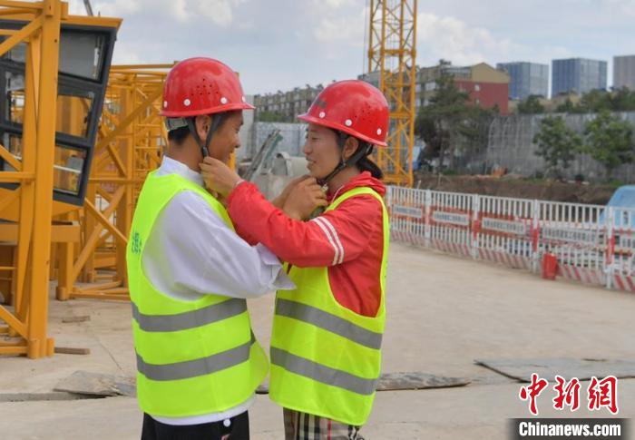 赵丽娟(右)和丈夫互相戴安全帽。赵丽娟同丈夫在一个建筑工地。赵丽娟说，他们夫妻认为安全是最重要的。　张瑶 摄