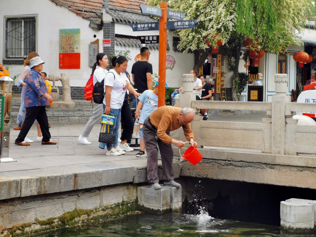 在曲水亭街，市民在泉水汇集而成的溪流旁取水。 新华社记者 张昕怡 摄