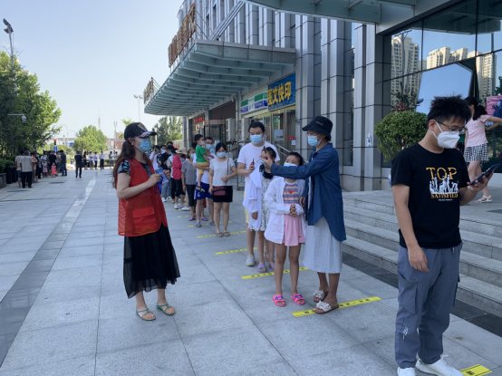 图为志愿者引导居民保持一米安全距离排队