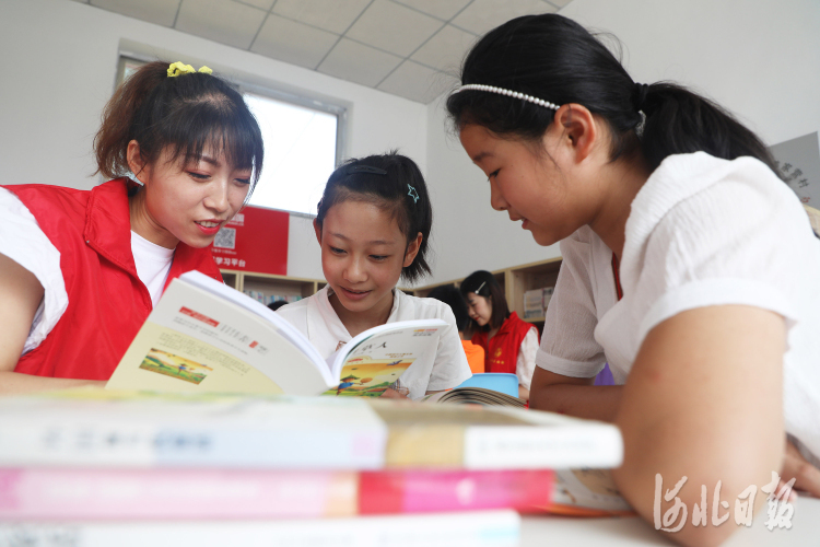 2021年8月13日，志愿者在河北省唐山市丰润区姜家营乡姜家营村陪伴孩子们读书。