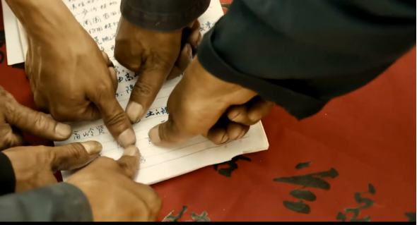 电影《八步沙》剧照——“六老汉”在承包治沙合同上集体按下红手印