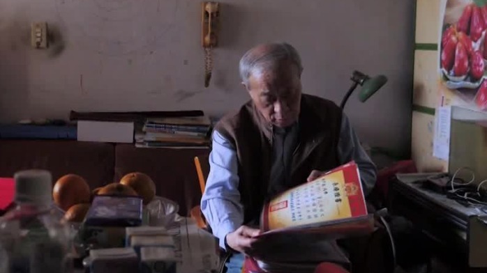 老人整理女儿上学期间获得的奖状，脸上洋溢出幸福的笑容