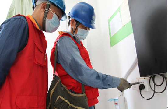 国网分宜县供电公司城区供电所共产党员服务队队员在分宜中学教室内对开关插座和线路进行检查。(彭雪琴 摄)