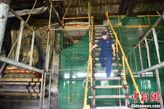 明教寺觉皇殿内搭满了脚手架，李晓洋每天在这里进行壁画修复。（张浪 摄）