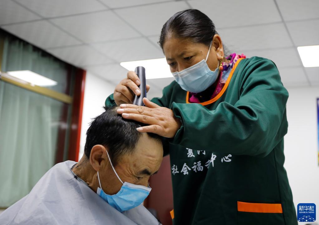 9月3日，在甘肃甘南夏河县拉卜楞综合社会福利中心，护理人员给老人理发。新华社记者 冯亚松 摄