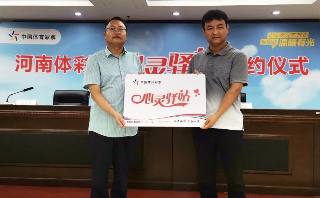 河南省体彩中心副主任王豪星（左）向郑州雨露心理咨询有限公司授牌