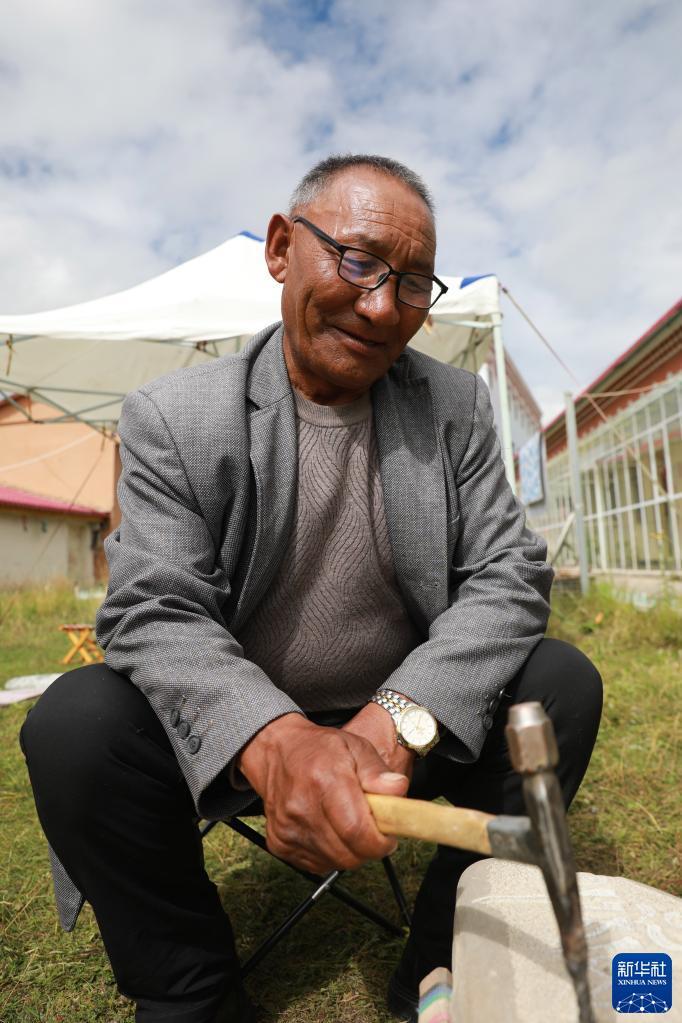 9月2日，在甘肃甘南碌曲县社会综合福利院，藏族老人旦正加木措在雕刻玛尼石。新华社记者 杜哲宇 摄