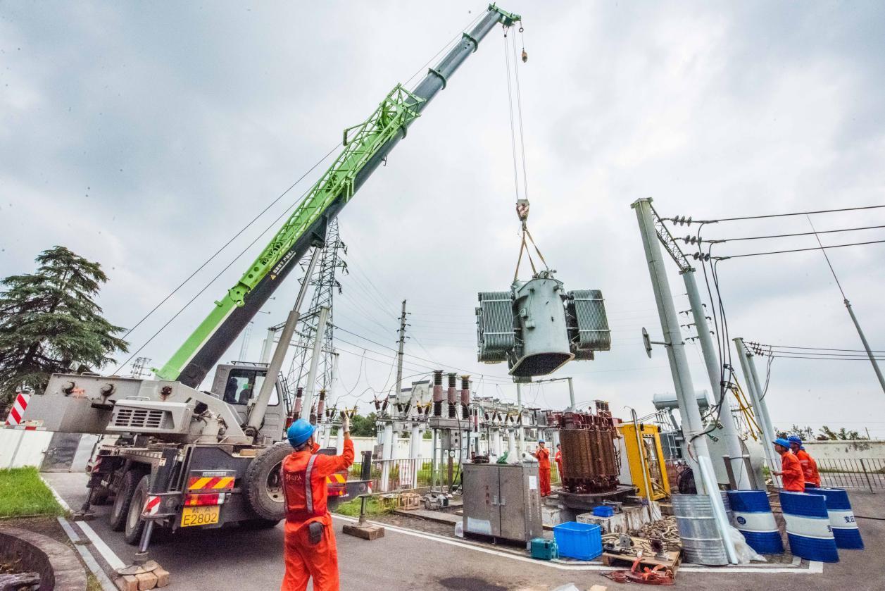 图为庐江县供电公司组织专业队伍吊装变压器外罩
