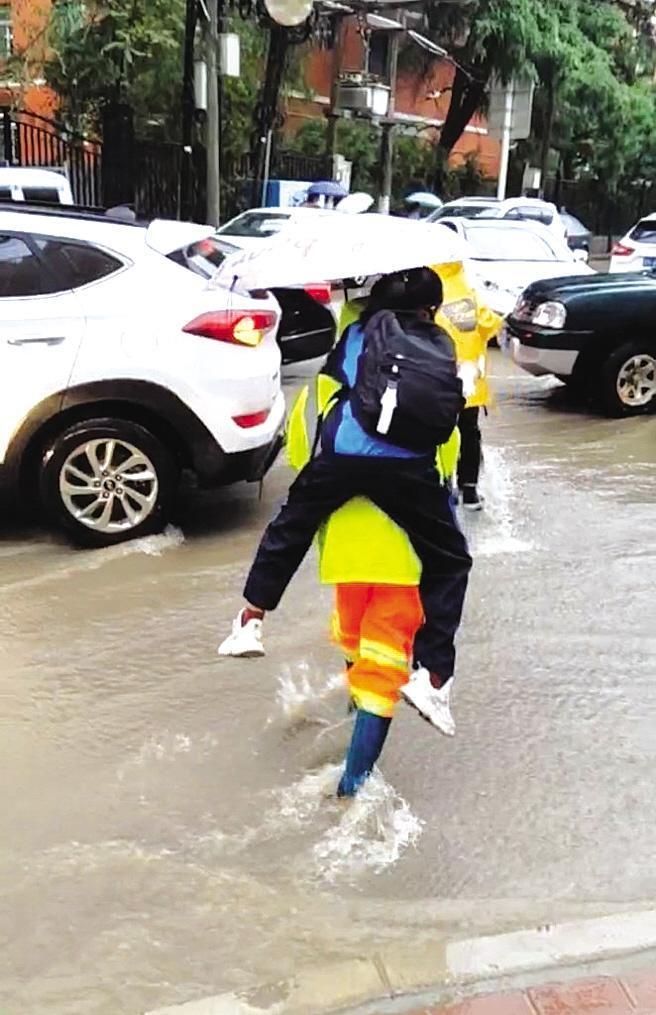 马路(视频截图) 兰州晚报讯 "那天下雨,看到环卫工背着孩子们趟过积水