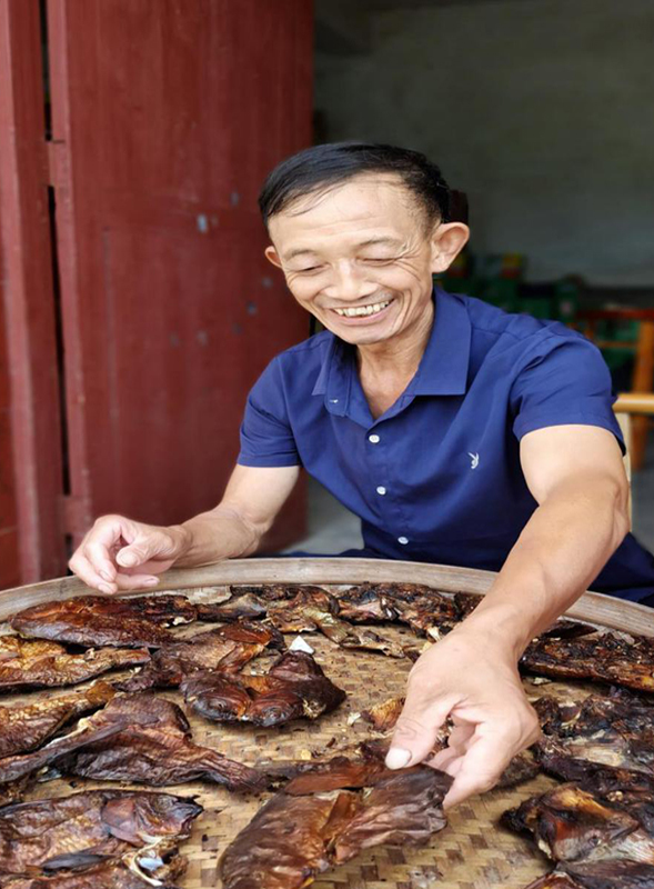 岩岭村村民何英善正在翻晒着熏鱼干
