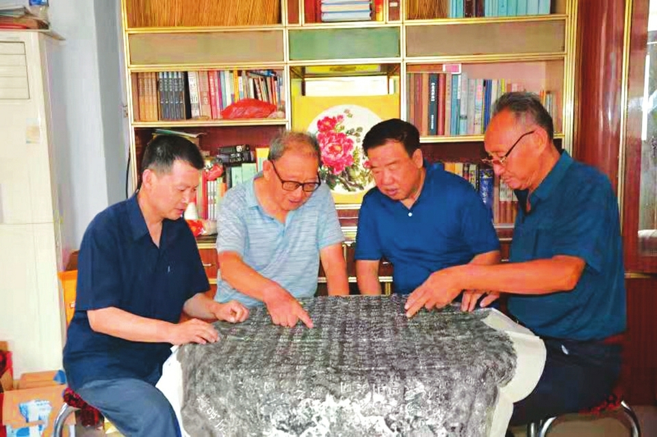 图为史万祥(右一)和退休返乡的卢江辉(右二),张益民(右三)一起,就拓片