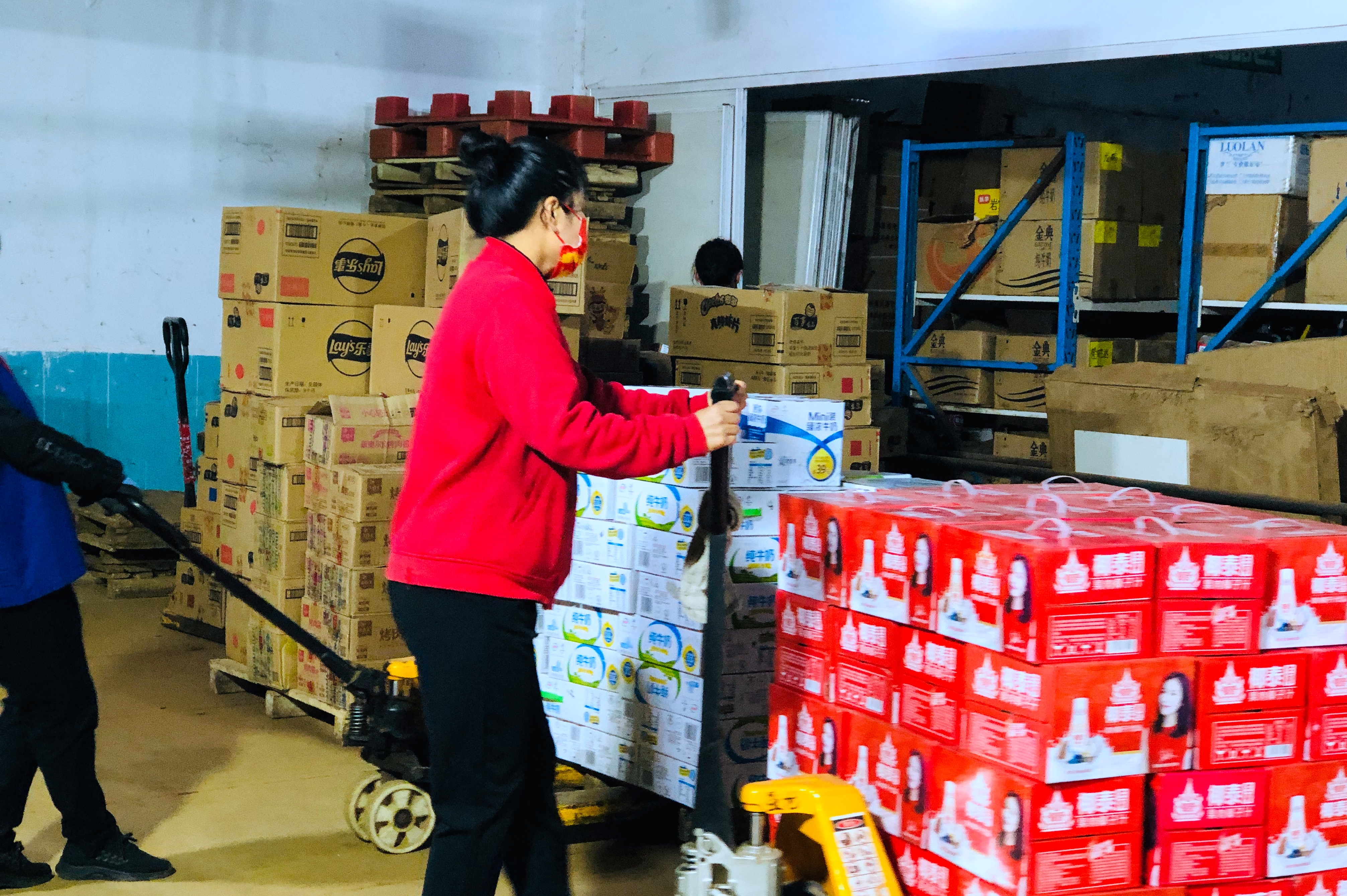 超市工作人员将成箱的奶制品摆上货架