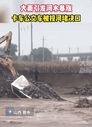 废旧公交车被投入洪水中封堵决口。/ 大象新闻