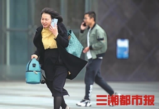 (10月11日,长沙市湘江中路,一名女士在大风中前行.